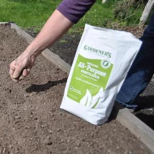 Spreading fertilizer on soil in a raised bed