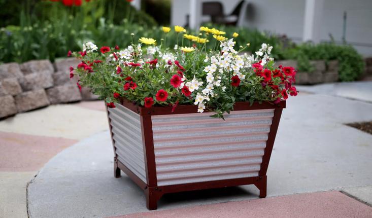 Galvanized Self-Watering Planter with flowers planted in it on stone patio