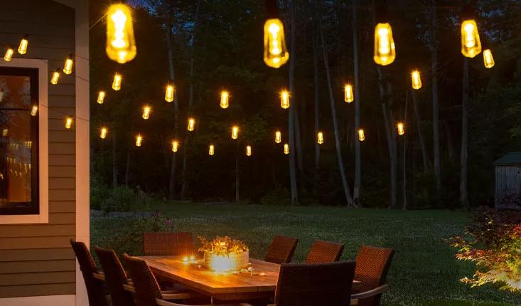 Luminites™ Solar String Lights hung above table on outdoor patio in evening light