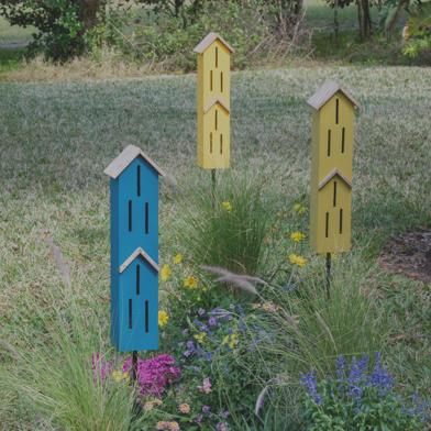 Butterfly Townhouse shelters in blue green and yellow in lawn among tall grass and wildflowers