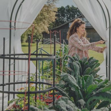 Woman pinning back Maxi Quilt Garden Cover with Kale and other vegetables growing under quilt