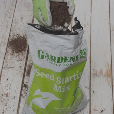 Person grabbing soil from a Seed Starting Mix 9 Qts bag
