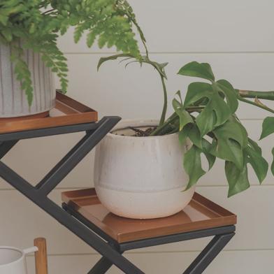 Closeup of plants on Crisscross Cascading Plant Stand with Copper Trays indoors in front of white wall