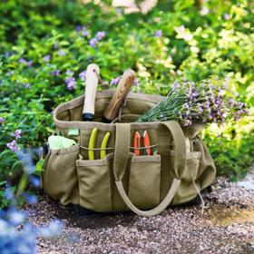 Gardener's Puddle Proof Tote filled with garden tools on mulched path in front of garden