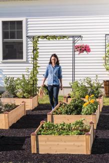 Woman walking down recycled rubber walkway among copper-capped raised garden beds